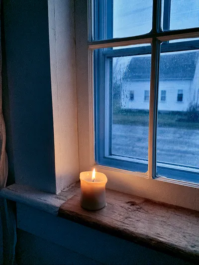 A lighted candle in the window.